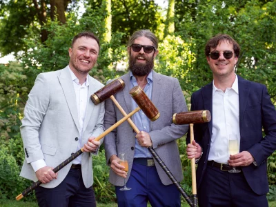 Three ben holding croquet clubs and champagne glasses