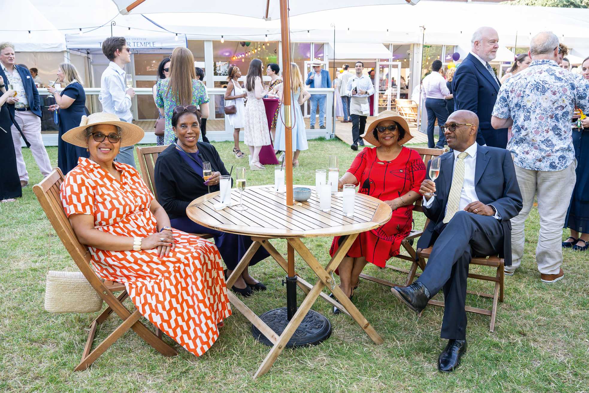 Two couples sitting around an outside table drinking champagne