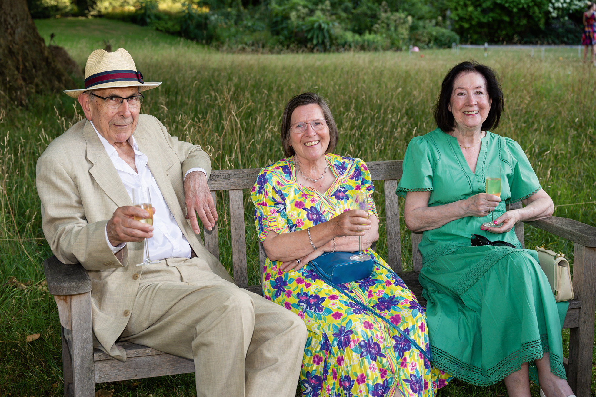 Three elderly people sitting in a bench in a garden