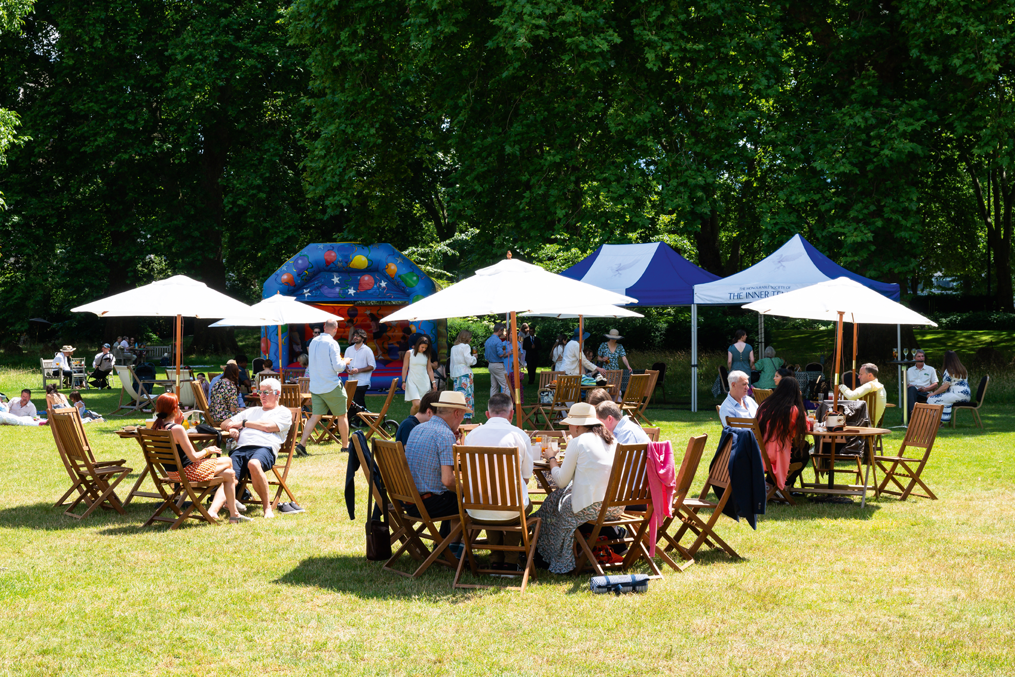 Groups of people at picnic tables with umbrellas 
