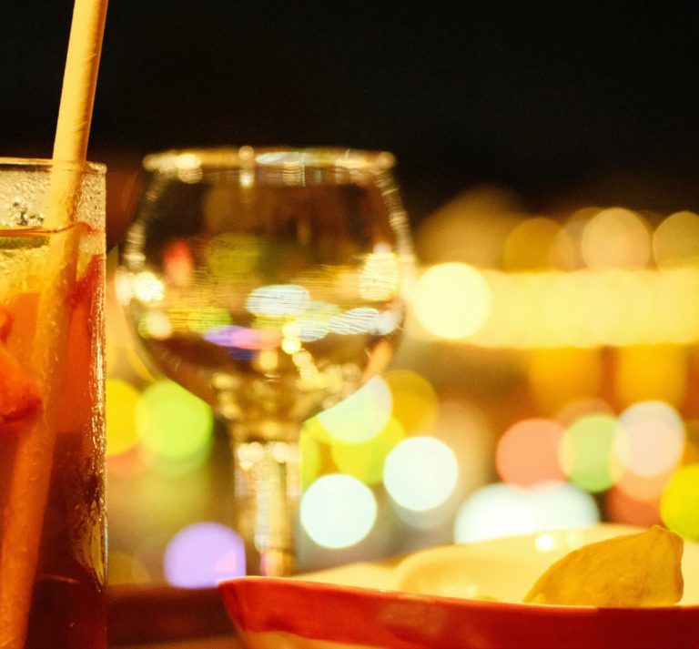 A wine glass catching the candlelight at dinner, promotional image for Bar Guest Night