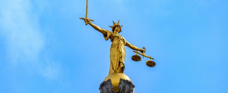 The statue of Lady Justice on the dome of the Old Bailey against a blue sky