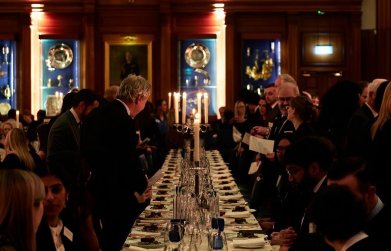 Students and members dining by candlelight in Hall at the Dinner to the Universities